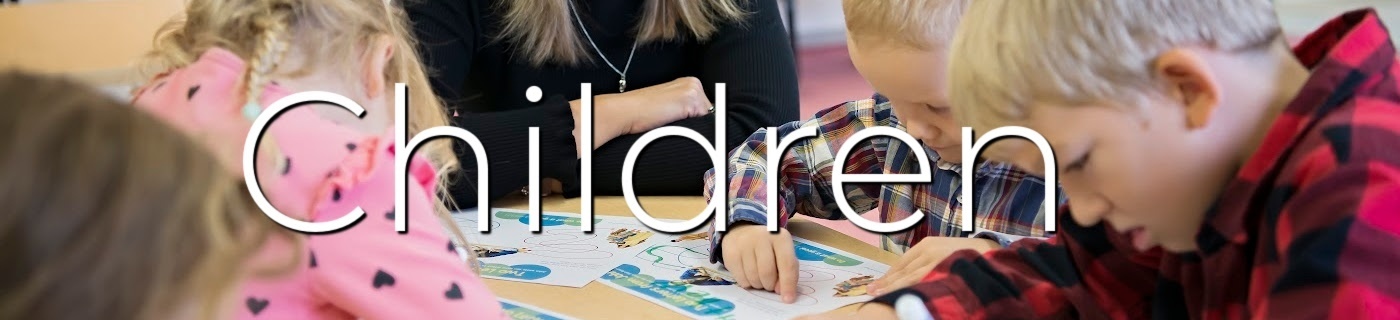 group of children at a table crafting with black/white lettering